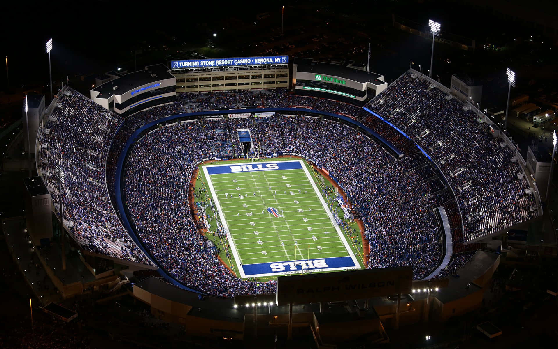 Thousands of football fans cheer inside a bright and vibrant football stadium.