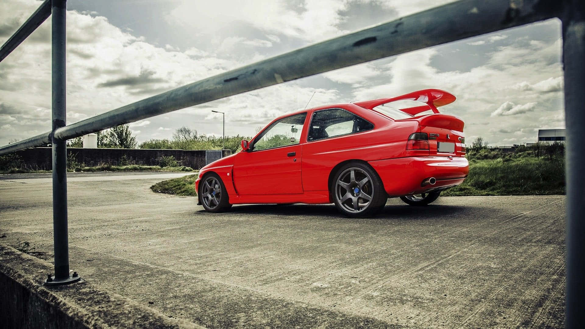 A sleek classic Ford Escort in vivid color with a vibrant background Wallpaper