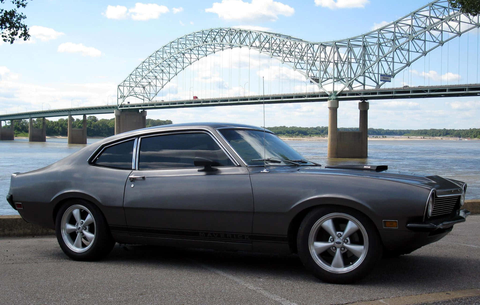 A Gray Car Parked In Front Of A Bridge