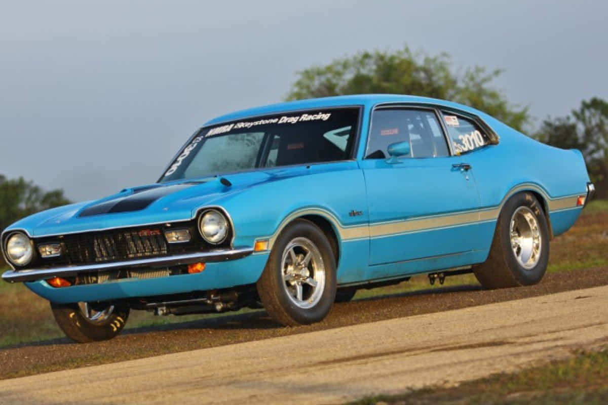 A Blue Muscle Car Is Driving Down A Dirt Road