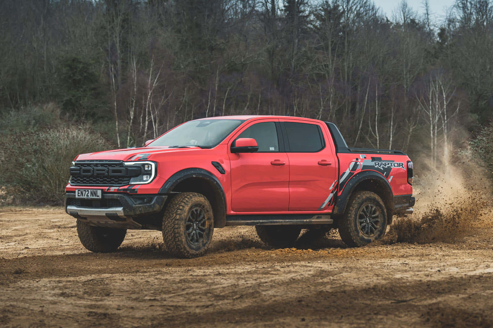 Ford Ranger Raptor - A Red Truck Driving Through A Dirt Field