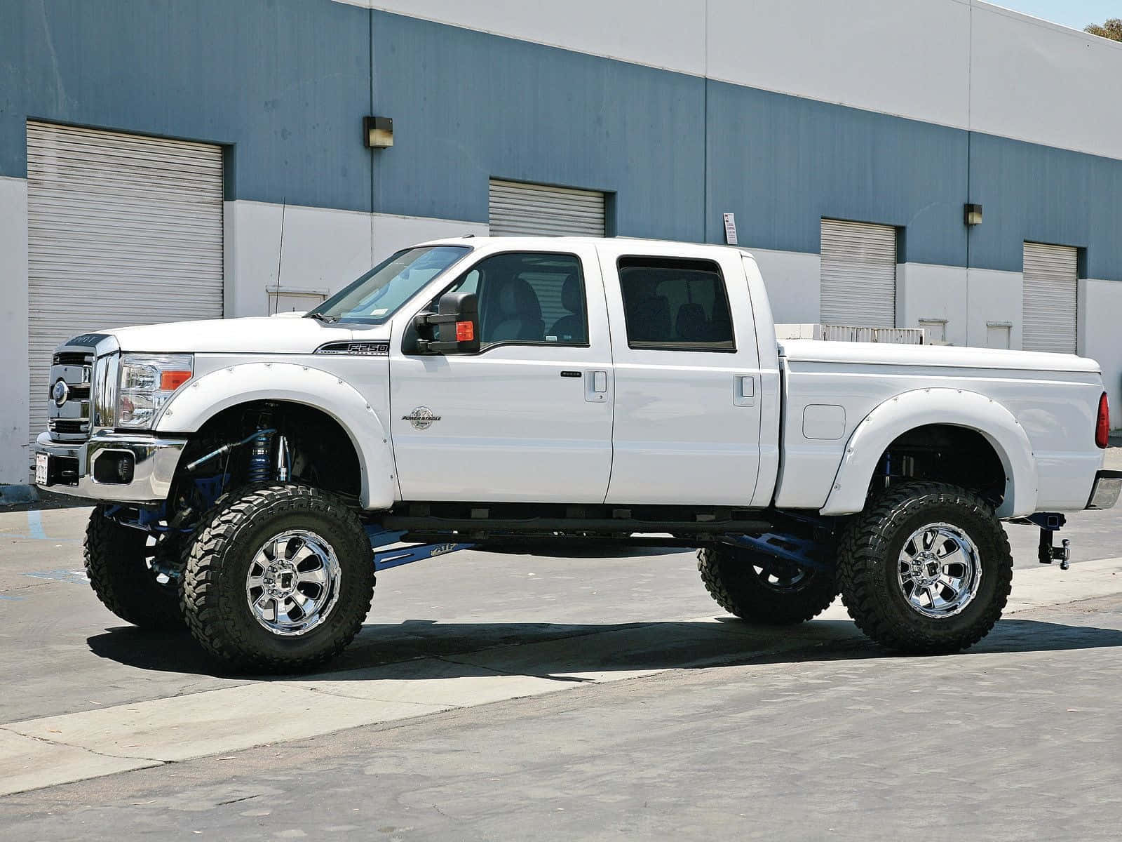 A White Ford F-250 Lifted Truck Parked In Front Of A Building Wallpaper