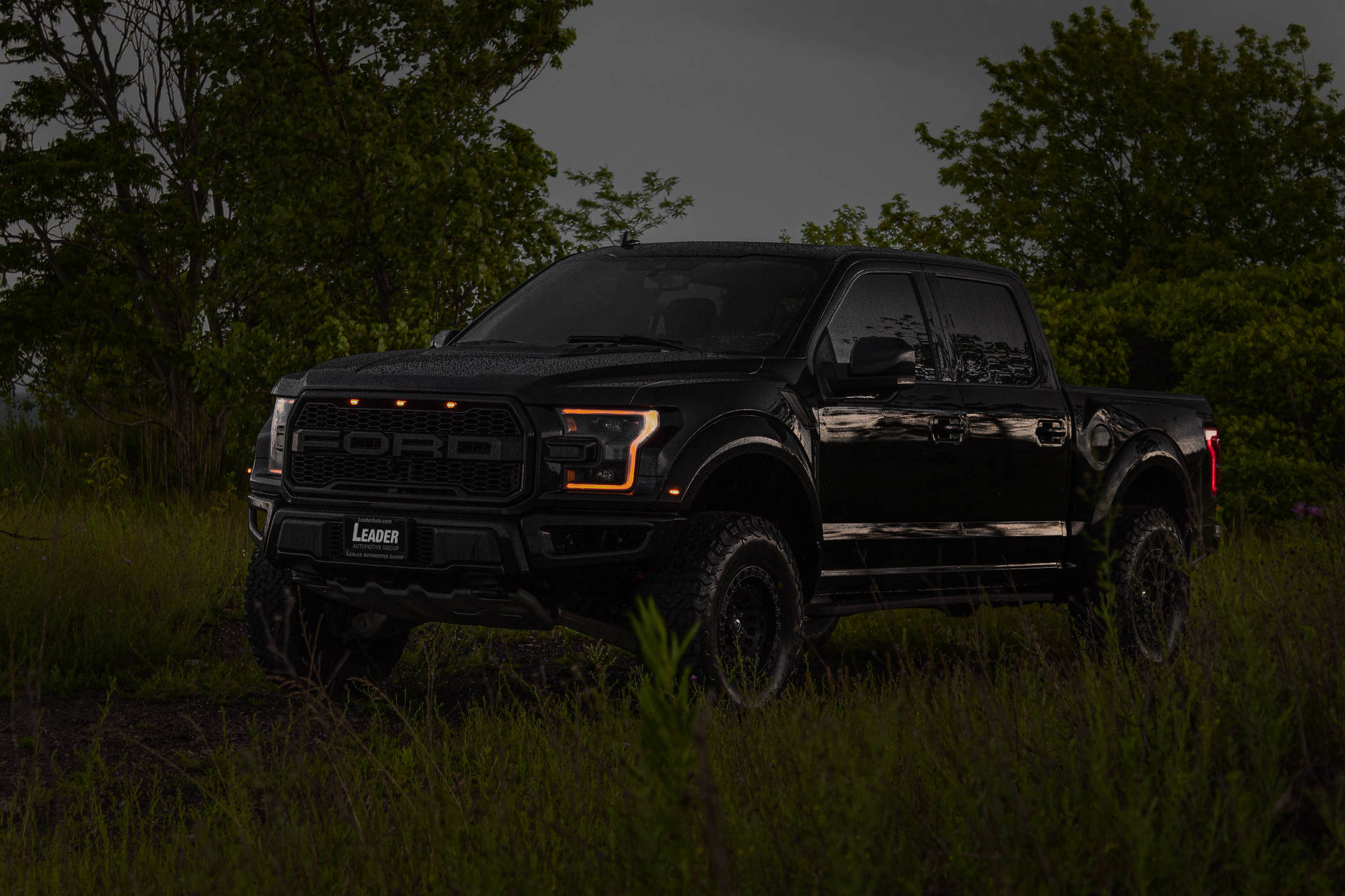 Powerful Ford Raptor with Vibrant Orange Headlights Shining in the Dark Wallpaper