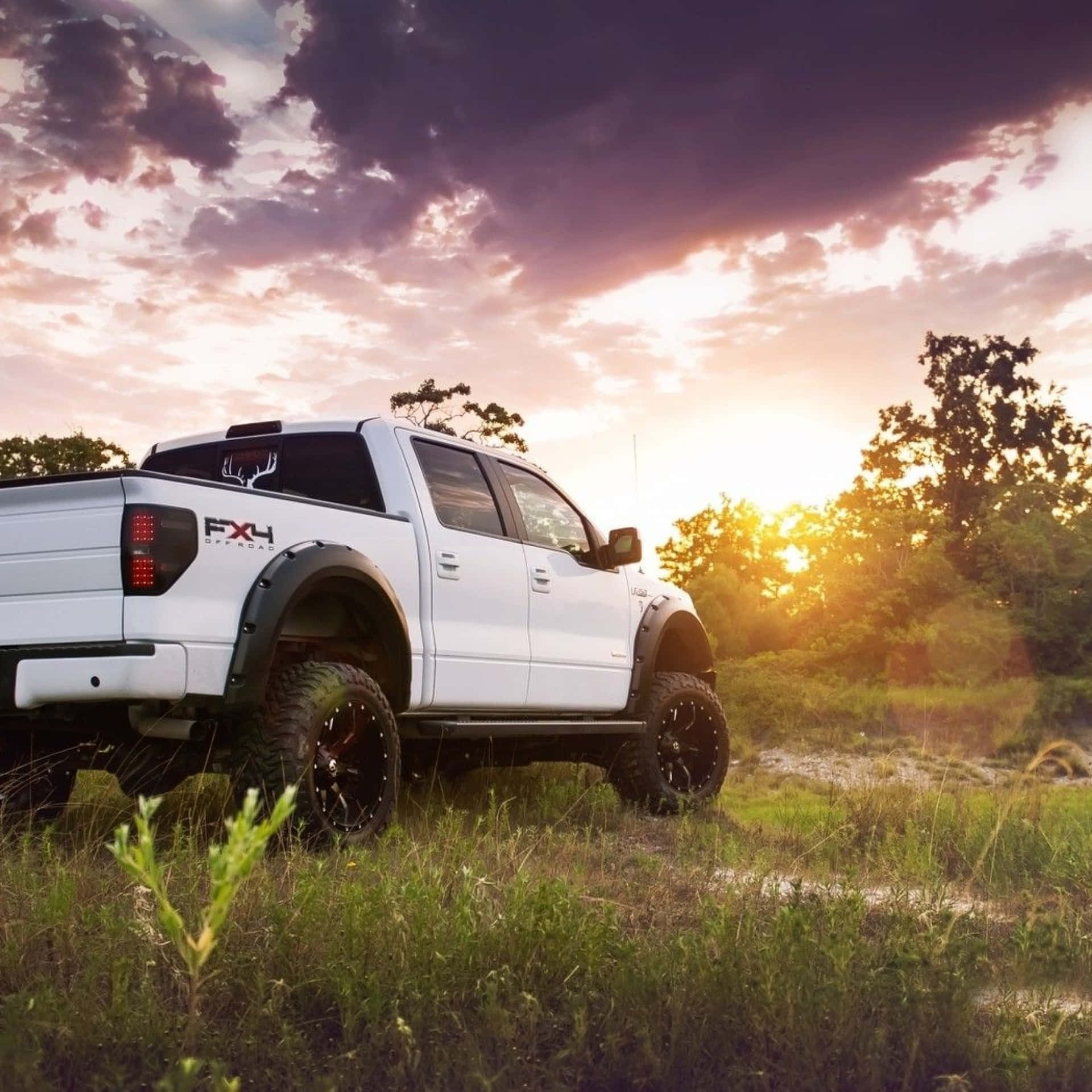 A White Truck Parked In A Field At Sunset Wallpaper