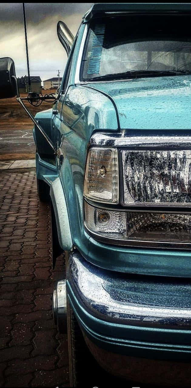 A Blue Car Parked On A Brick Road Wallpaper