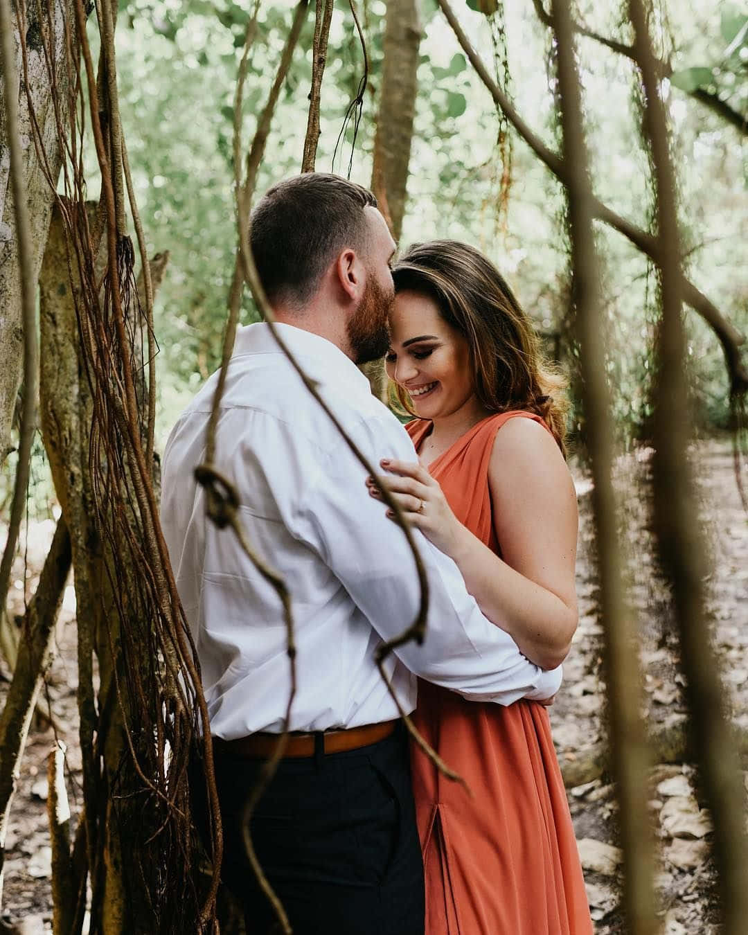 A Couple Embraces In The Woods During Their Engagement Session