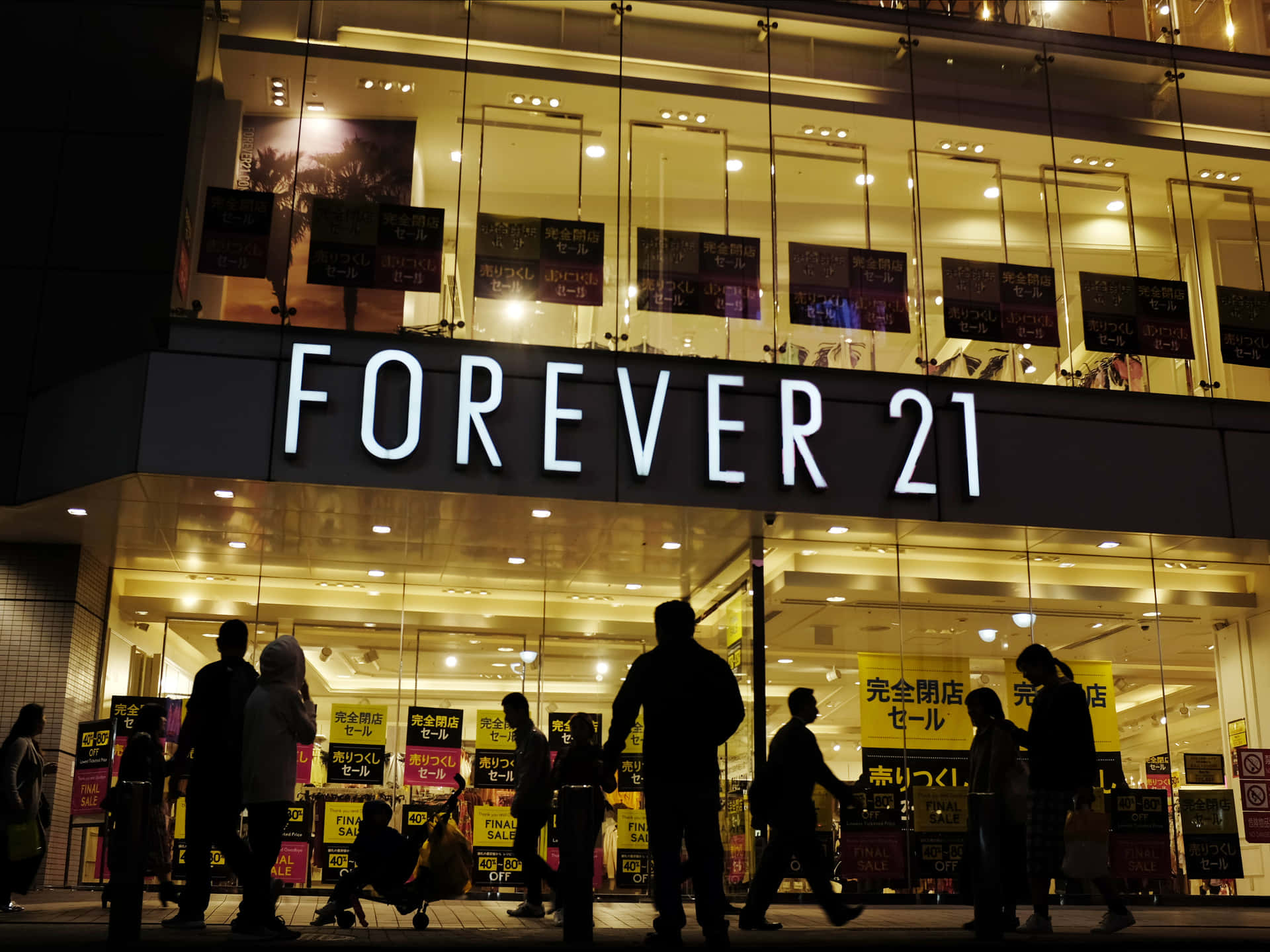 A Group Of People Walking Past A Forever 21 Store At Night