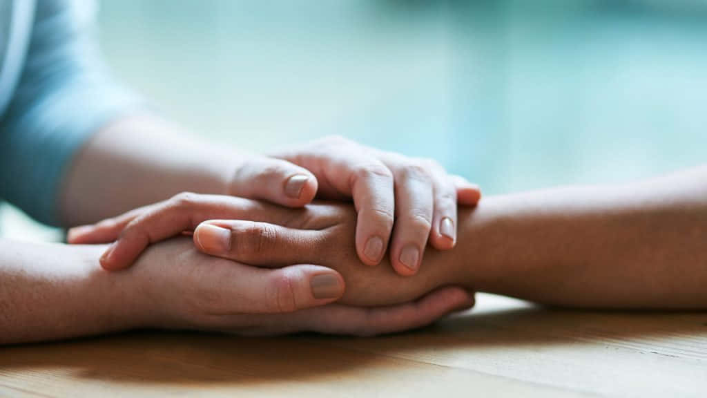 Two People Holding Hands On A Table
