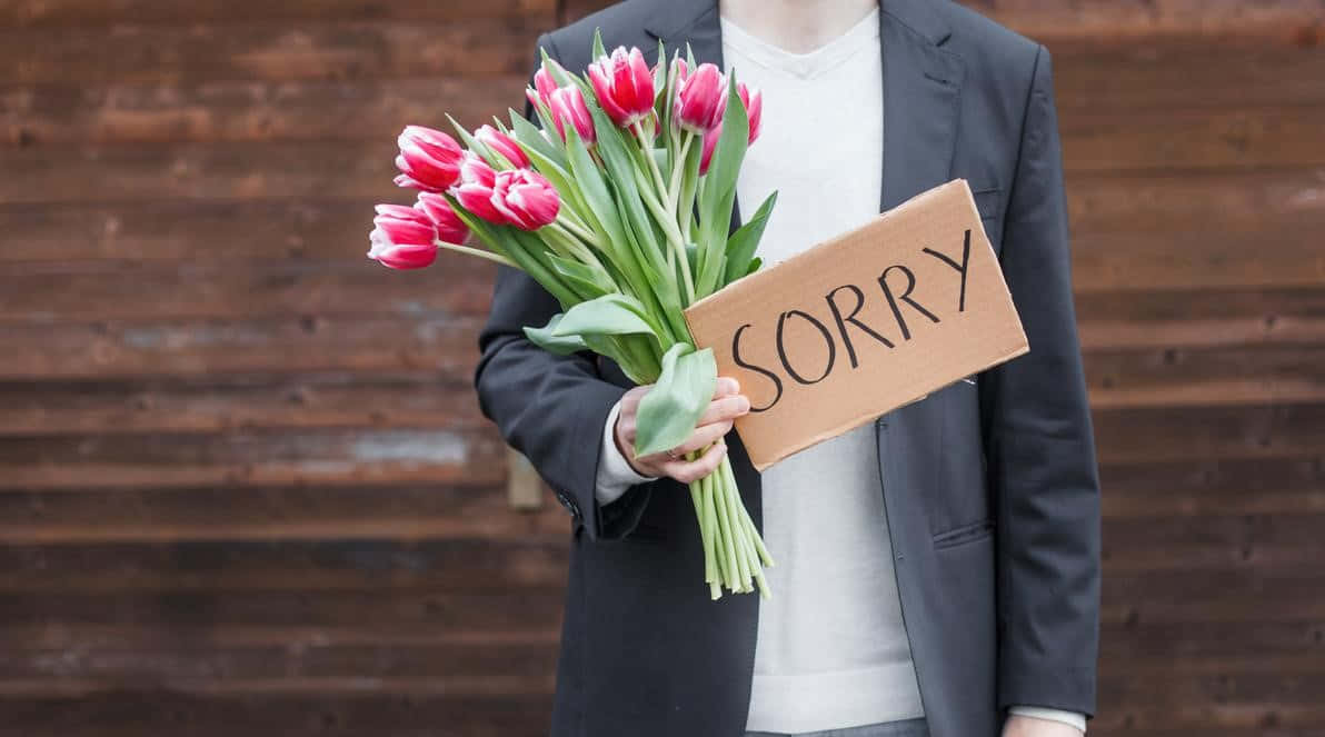 A Man Holding A Sign That Says Sorry