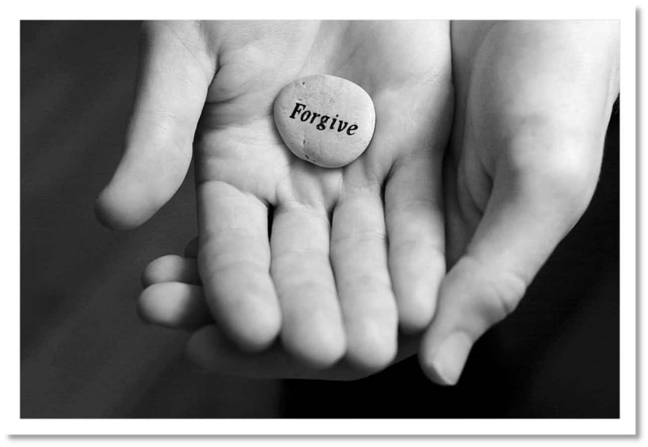 A Person Holding A Stone With The Word Forgive Written On It