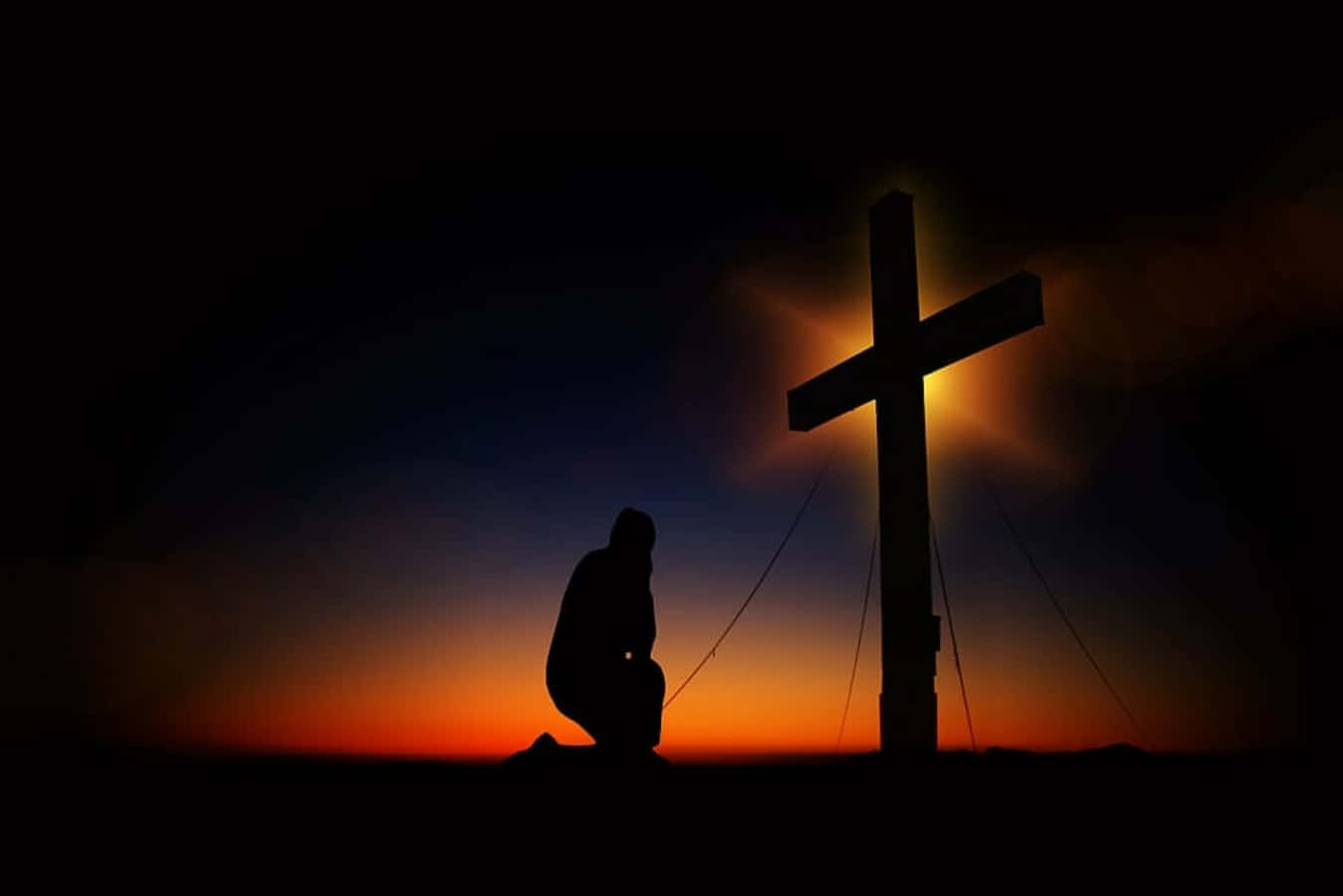 A Man Kneeling At The Cross At Sunset