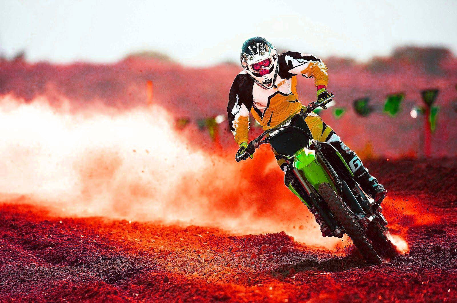 Eineperson Fährt Auf Einem Dirt-bike Über Ein Rotes Feld. Wallpaper