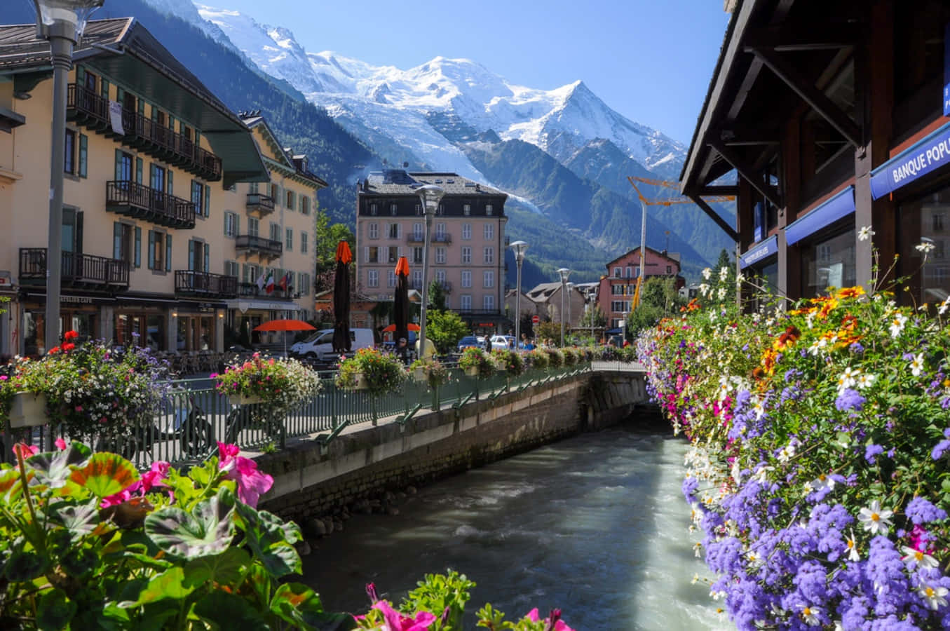 A River With Flowers And Mountains In The Background
