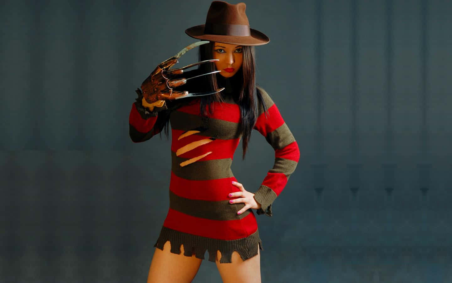 Freddy Krueger menacingly poses in a dark, eerie setting with his iconic glove and hat