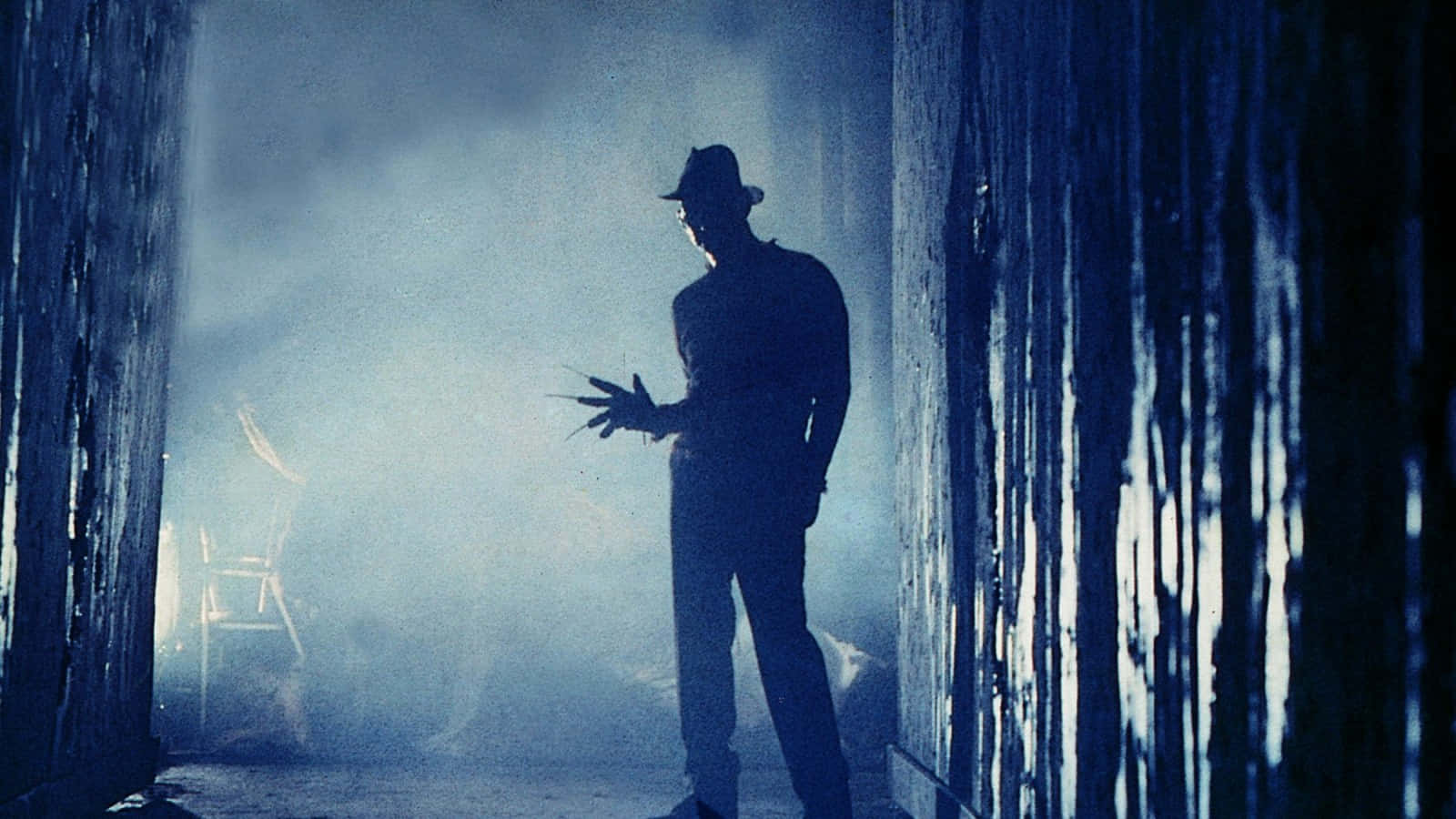 Freddy Krueger menacingly stares with his infamous glove and hat in a dark atmosphere