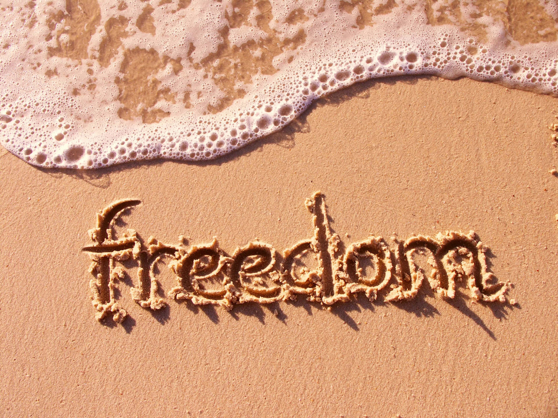 Freedom Written In Sand On A Beach