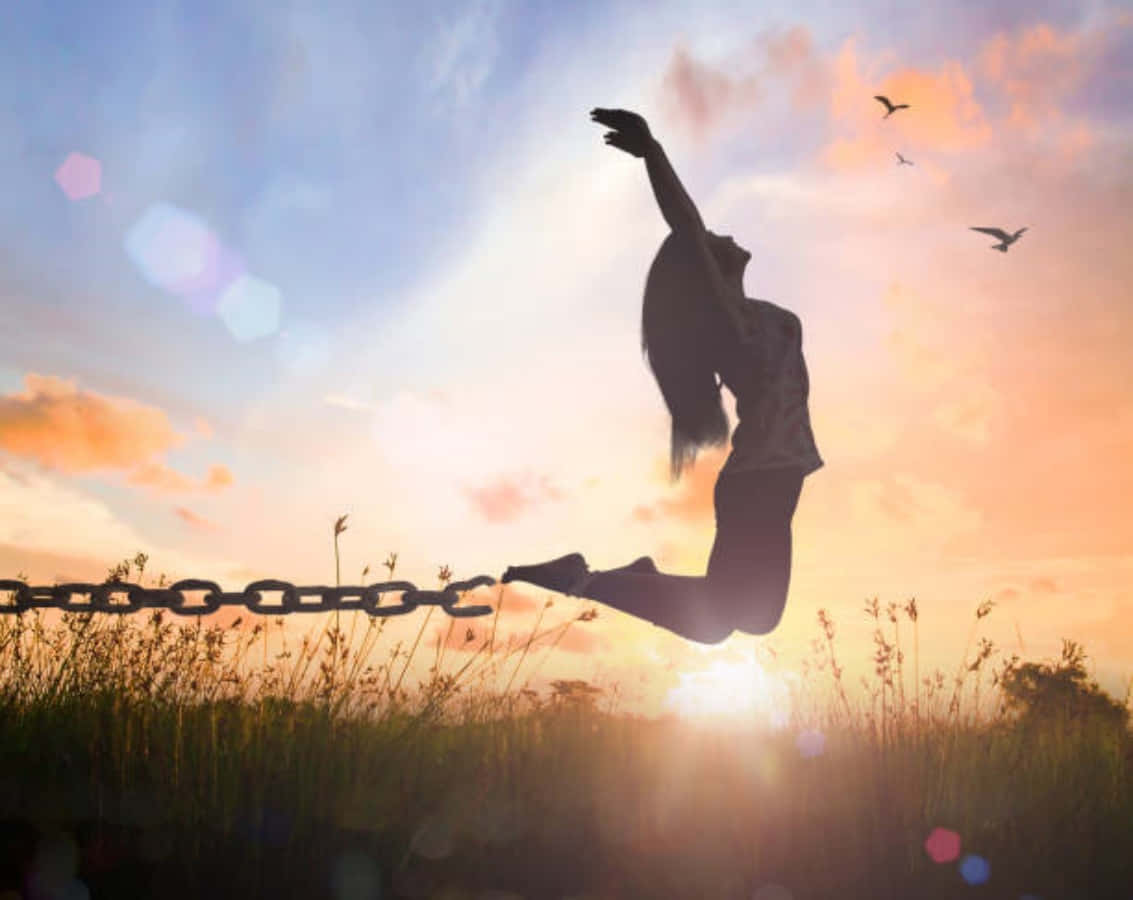 Silhouette Of A Woman Jumping On A Chain At Sunset