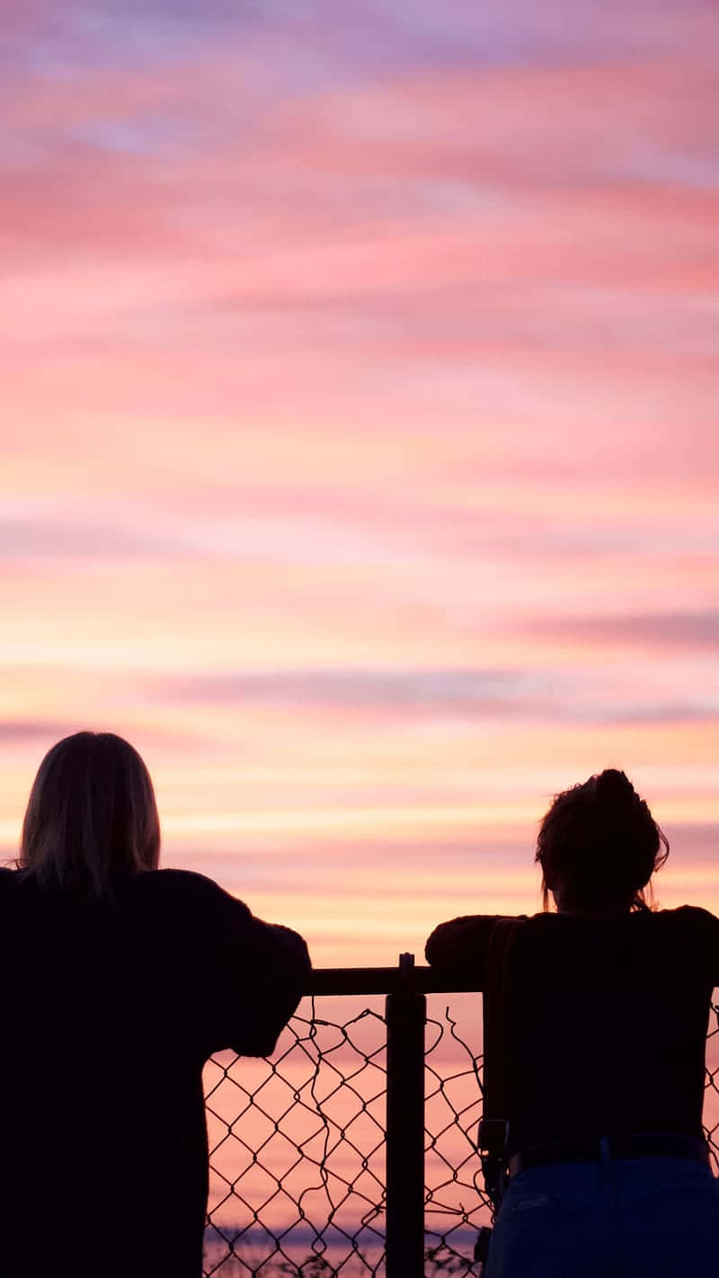 Friends Admiring Sunset Together Wallpaper