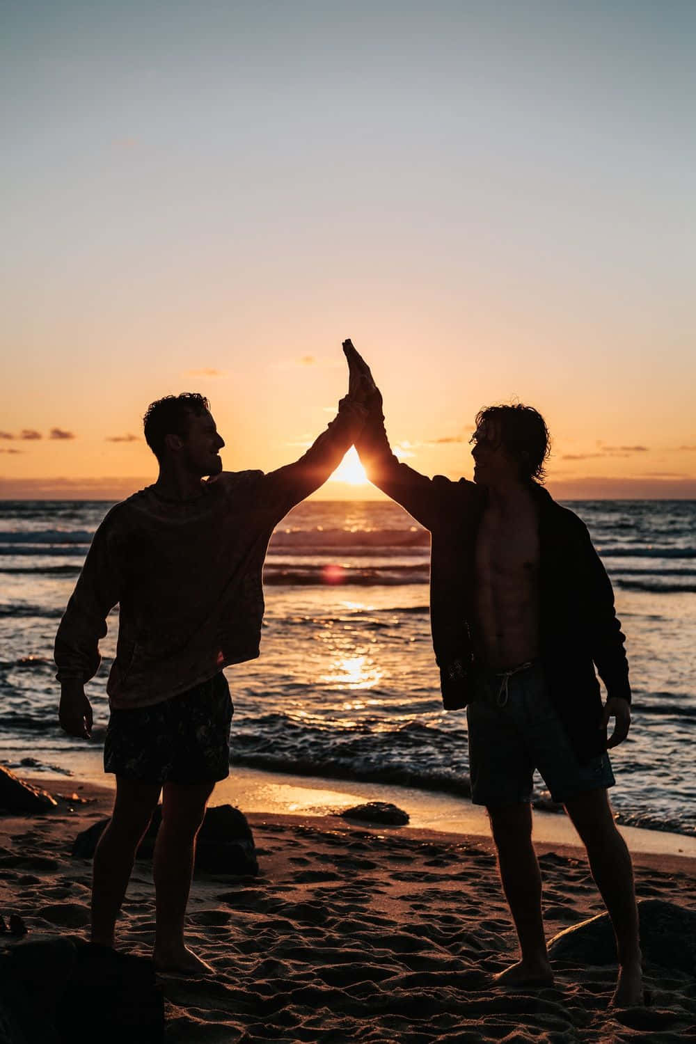 Freundschaftlicherhigh Five Am Strand Beim Sonnenuntergang Bild