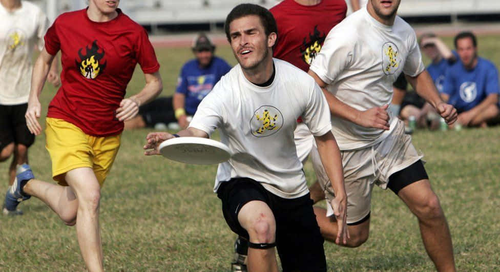A Group Of Men Running For A Frisbee