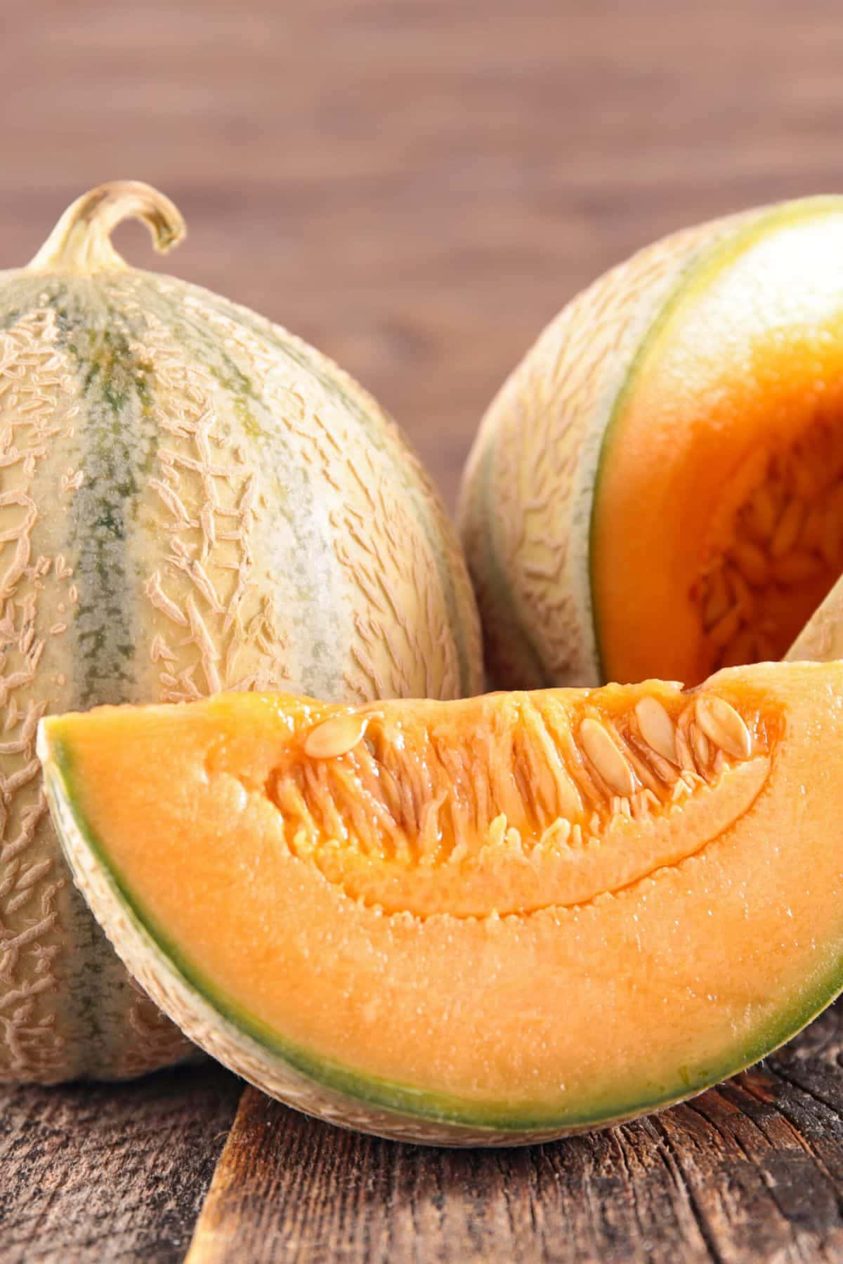 A Melon Is Cut In Half And Sitting On A Wooden Table