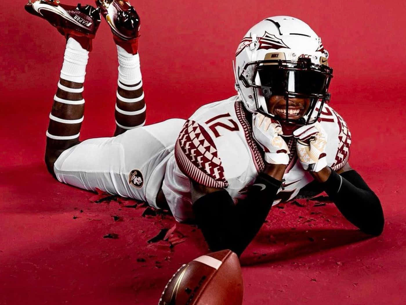 A Football Player Laying On The Ground With His Helmet On Wallpaper