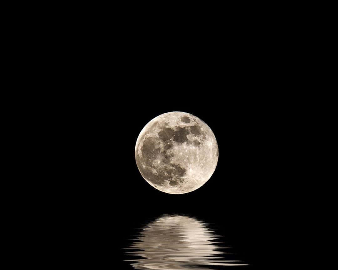 a full moon is seen in the water