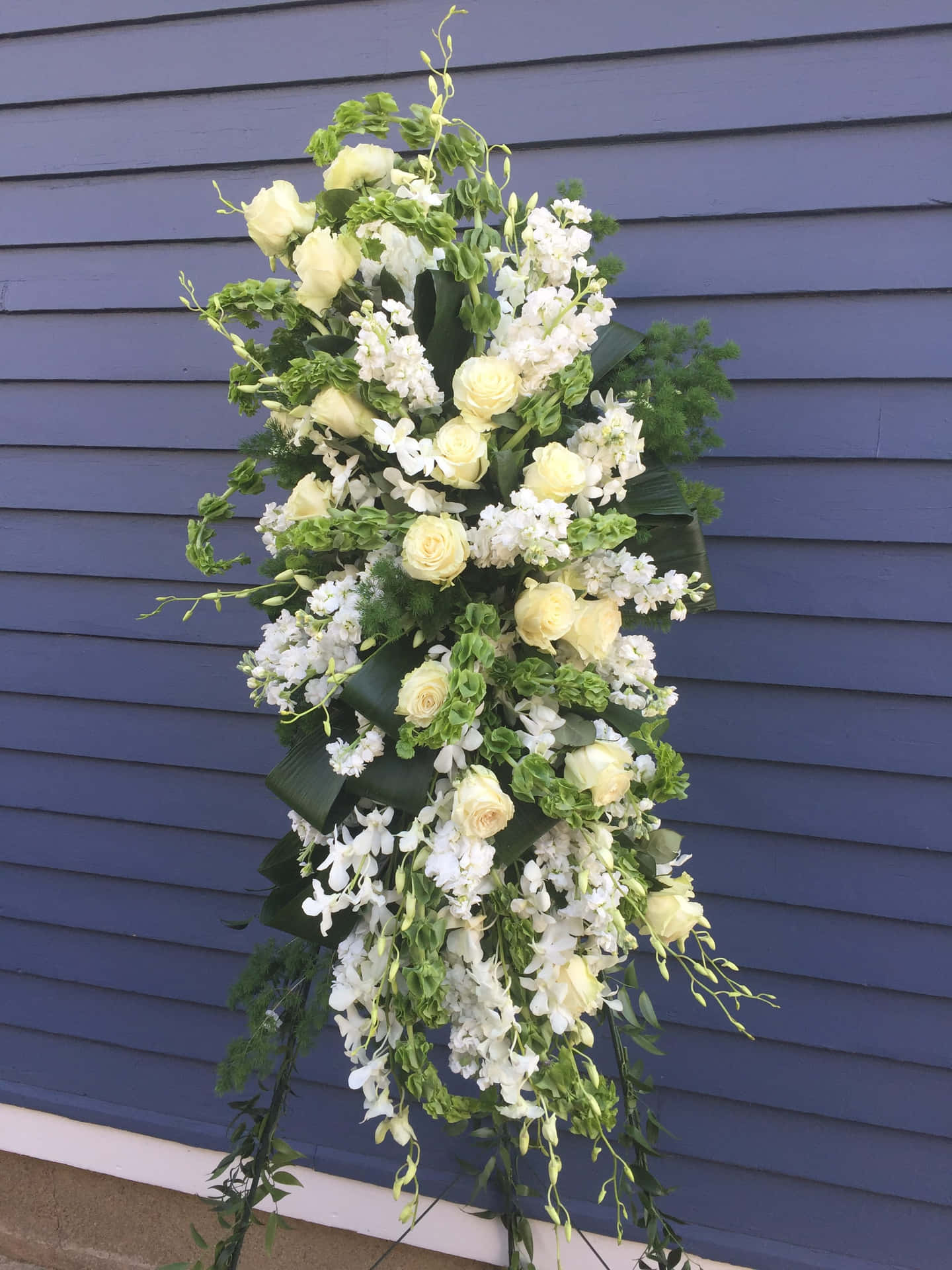 A White And Green Funeral Spray Hanging From A Wall