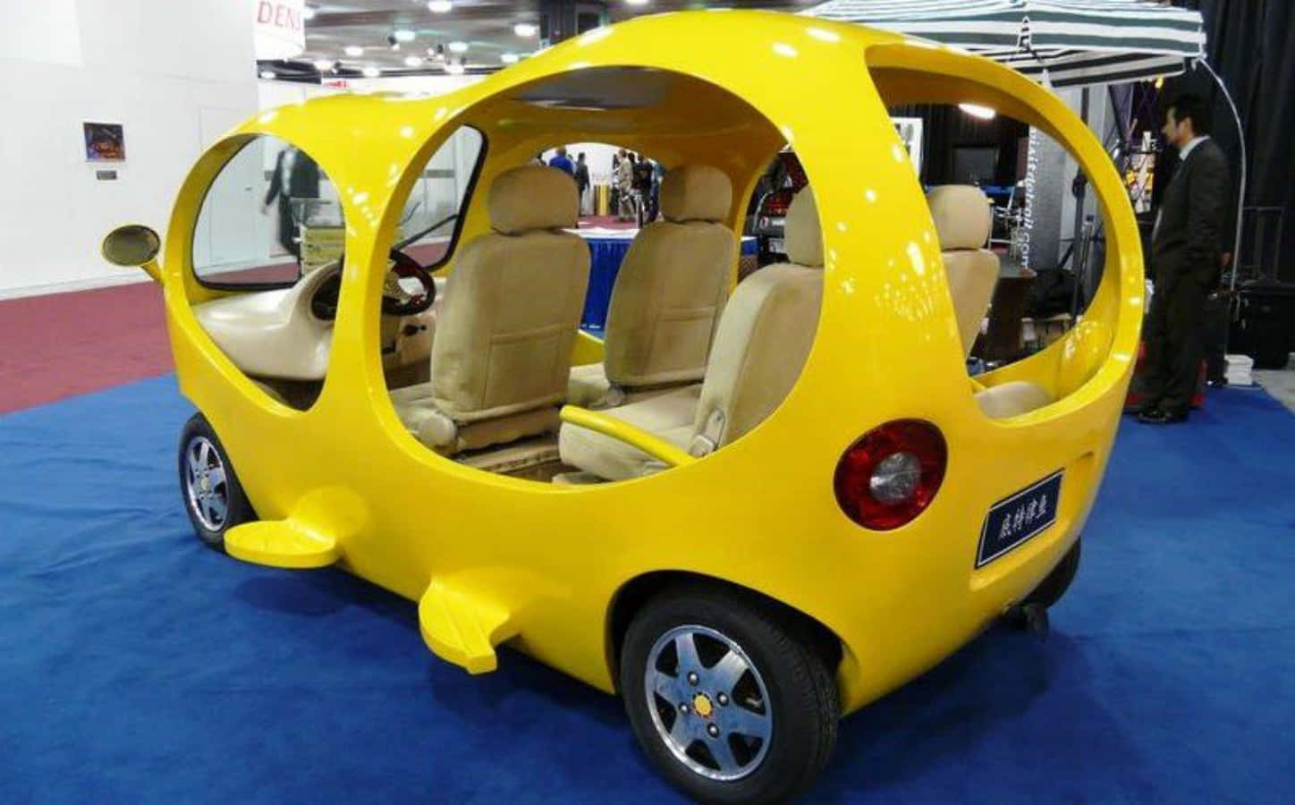 A Yellow Car With Two Seats On Display At A Show