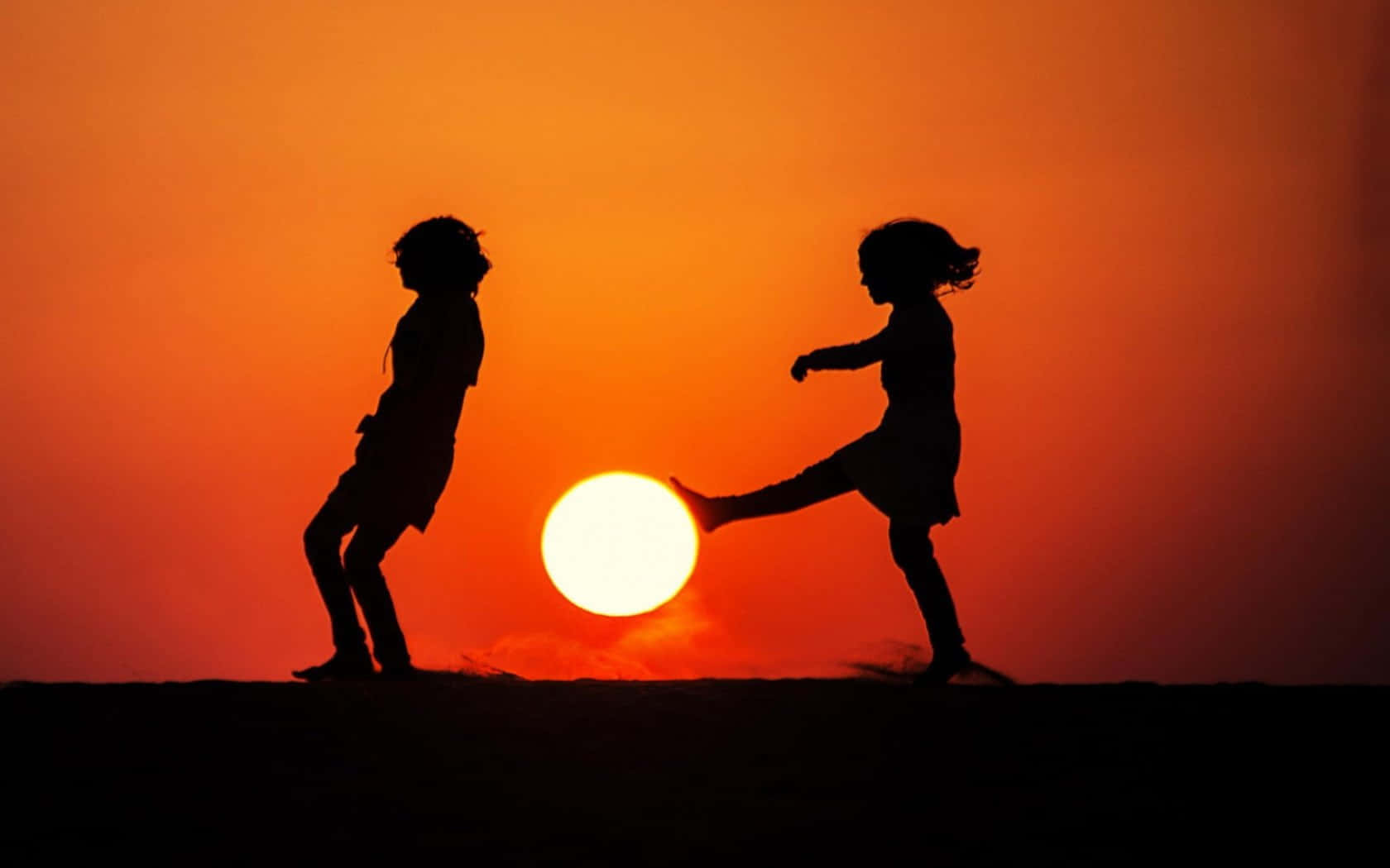 Silhouette Of Two Children Playing Soccer