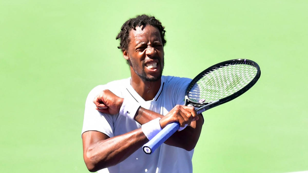 Gael Monfils in Focused Action against a Green Background Wallpaper