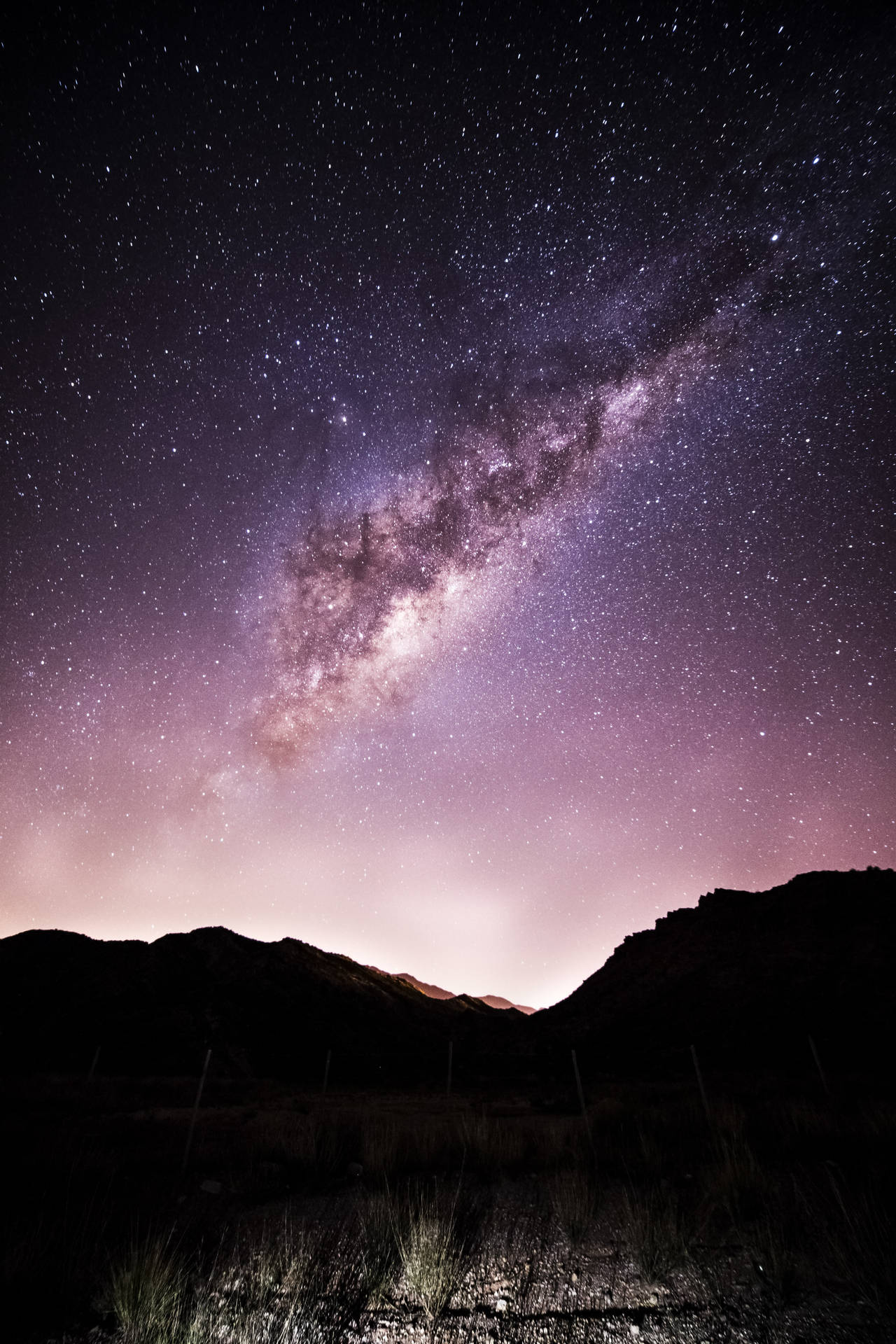 Galaxiaen El Cielo Sobre Montañas De Color Morado Oscuro Para Iphone. Fondo de pantalla
