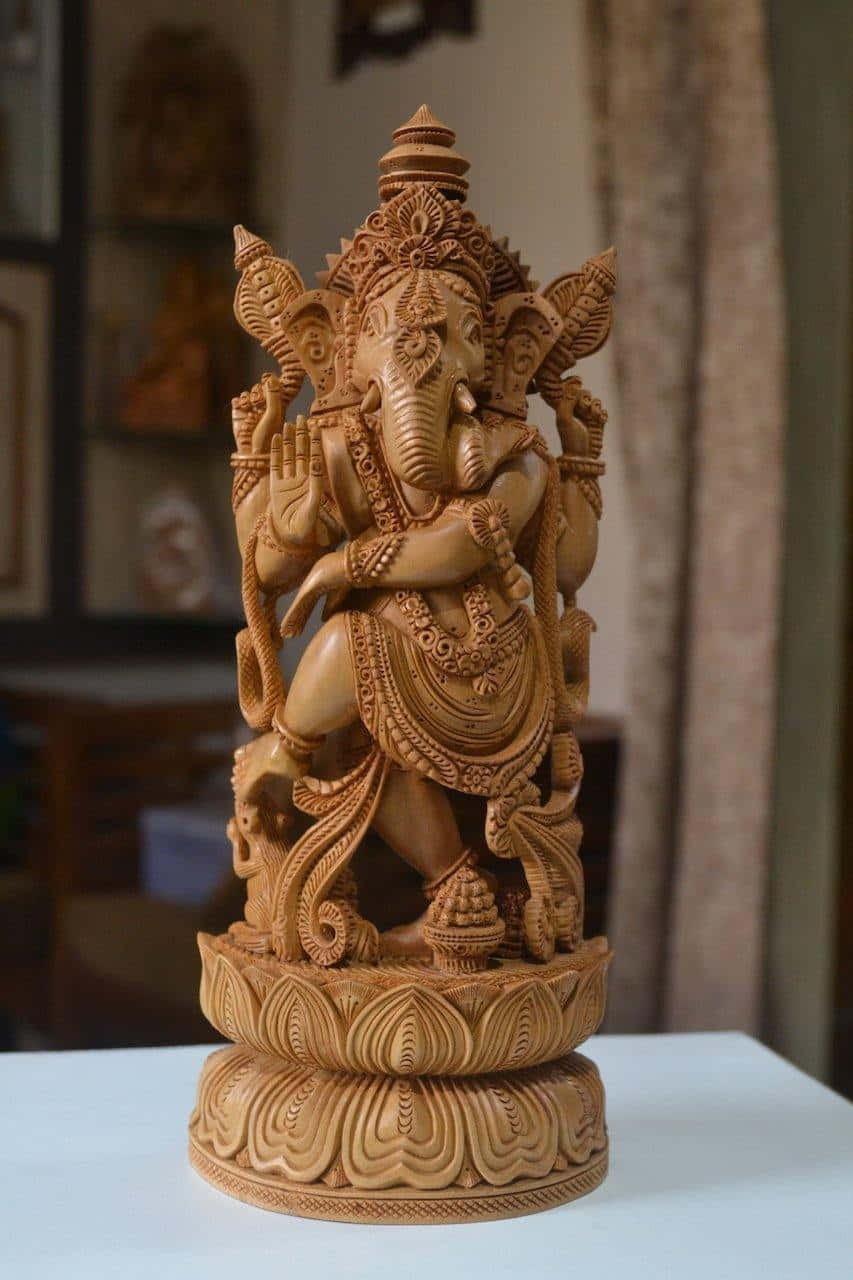 A Wooden Statue Of Ganesha Sitting On A Table