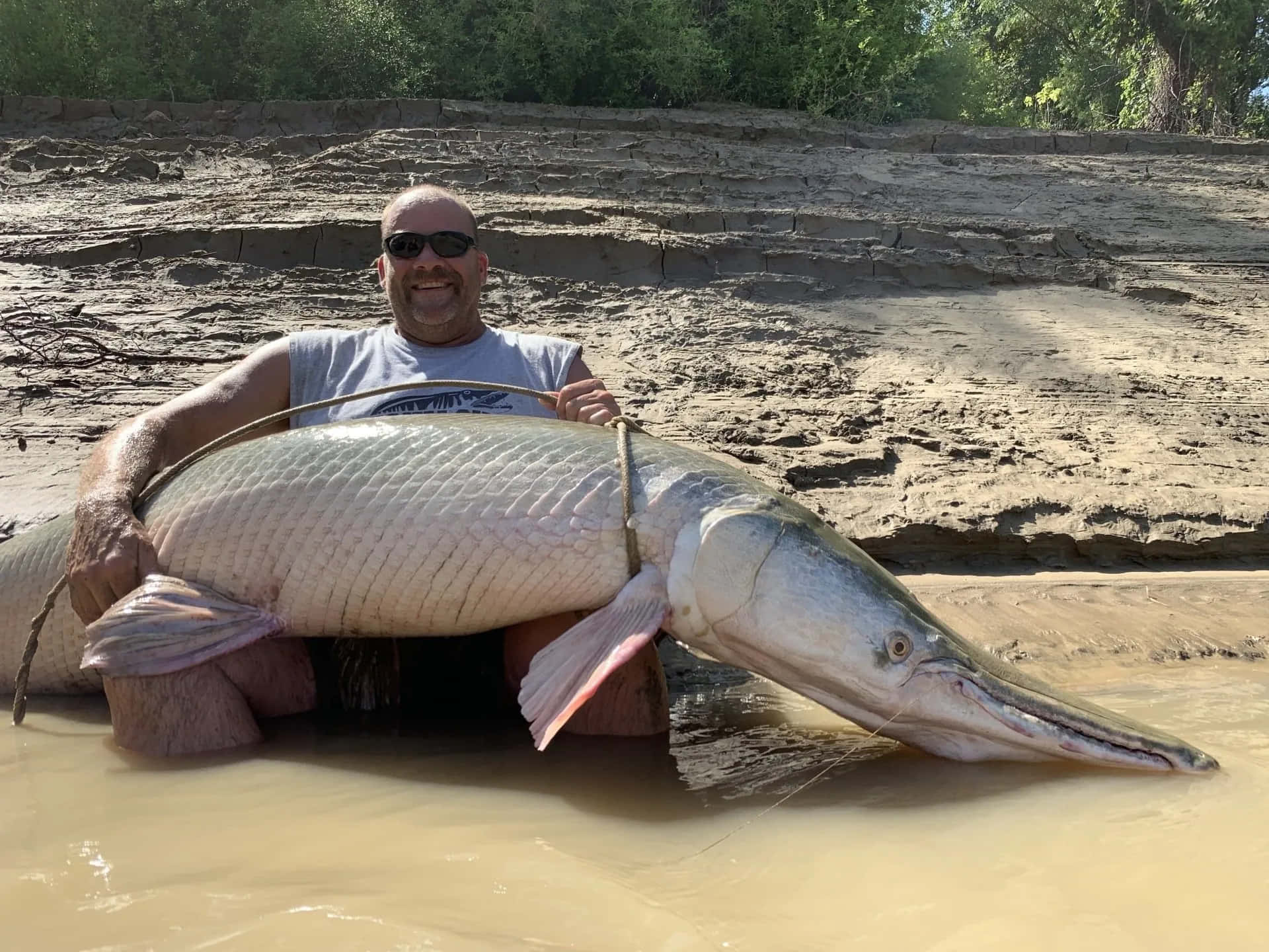 A Man Holding A Large Fish In The Water