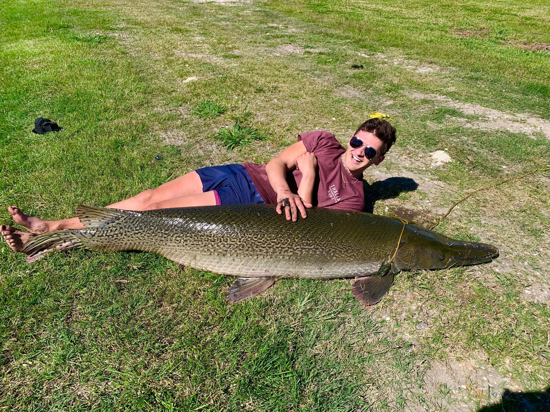 A Man Laying On The Grass With A Large Fish