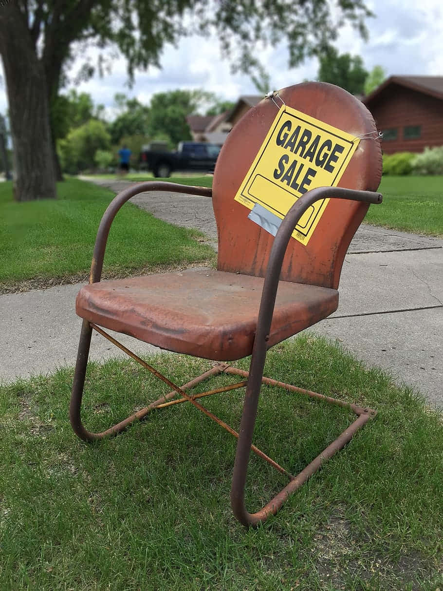 A Rusty Metal Chair With A Garage Sale Sign Wallpaper