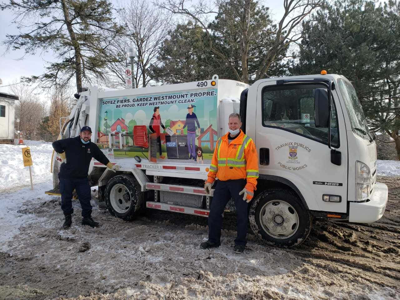 Two Men Standing Next To A Garbage Truck In The Snow
