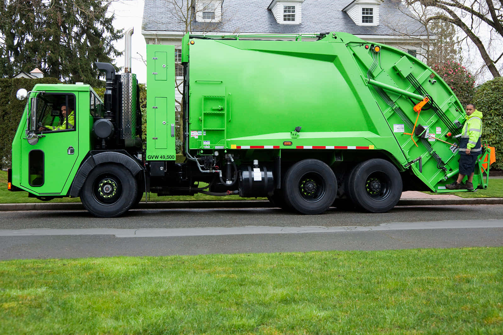A modern garbage truck collecting trash in an urban environment.