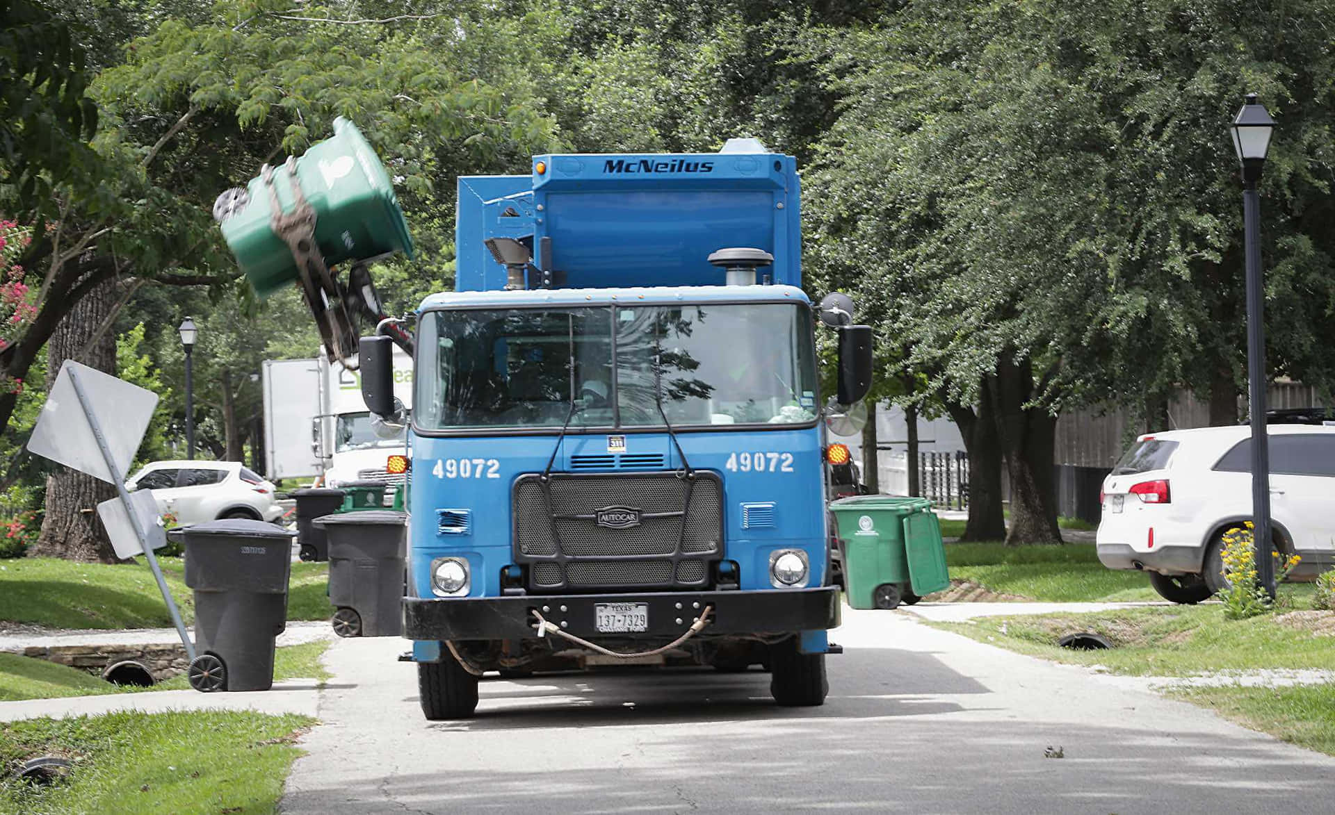 A Blue Truck Driving Down A Street