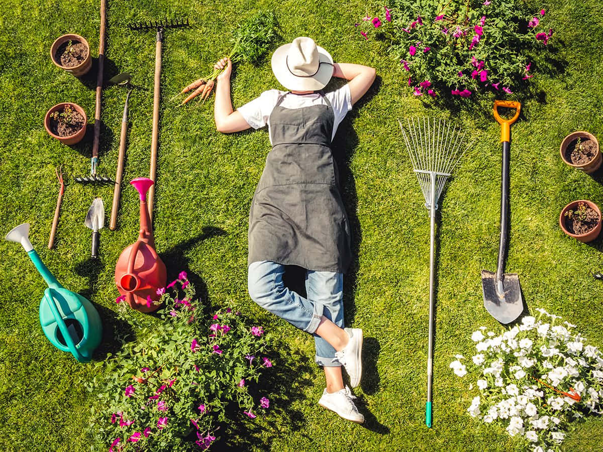 Woman Laying On The Grass With Gardening Tools