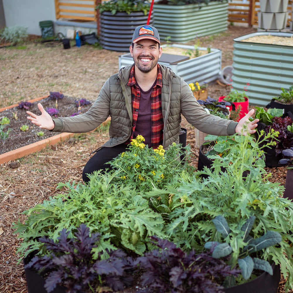 Einmann Kniet Vor Einem Garten Mit Gemüse.