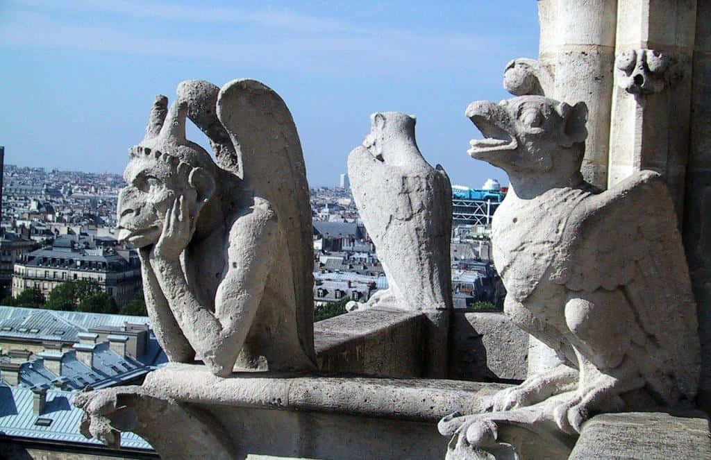 A Group Of Statues On The Ledge Of A Building