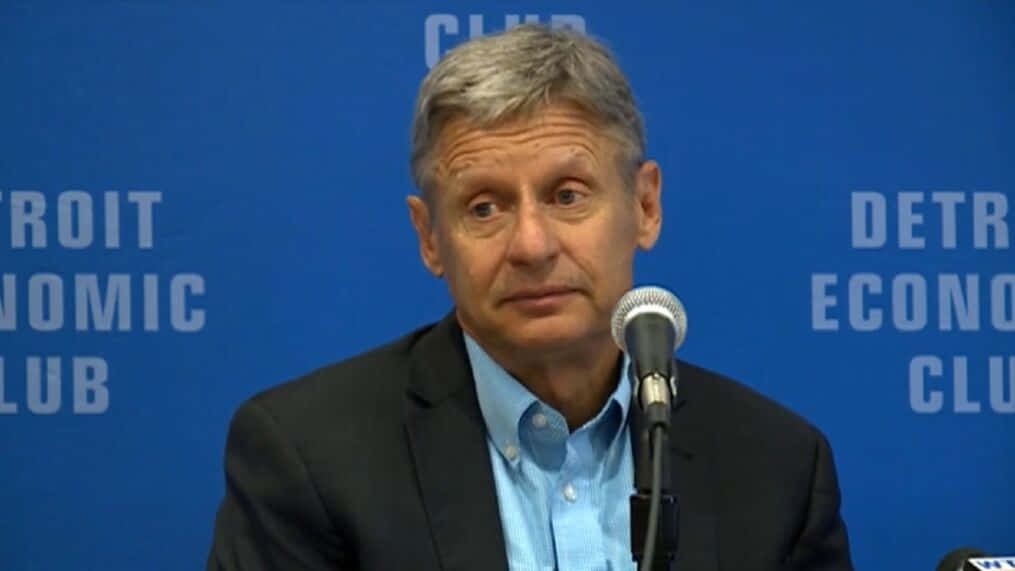 Gary Johnson With Microphone And Blue Backdrop Wallpaper