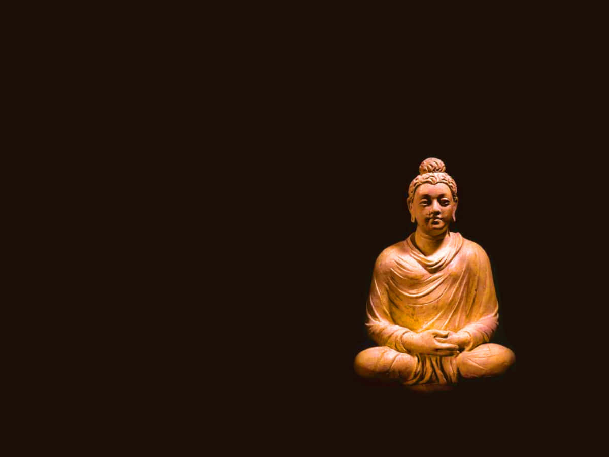 A Buddha Statue Is Sitting On A Dark Background