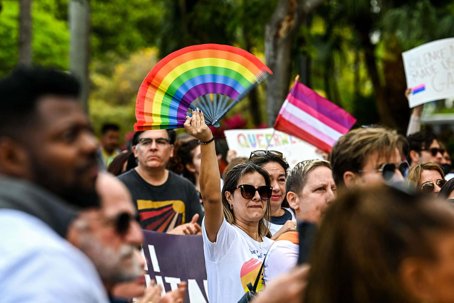 A Group Of People Holding Up A Rainbow Flag