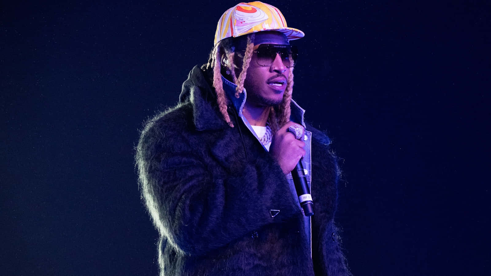 A Man In A Fur Coat And Hat Is Holding A Microphone Wallpaper