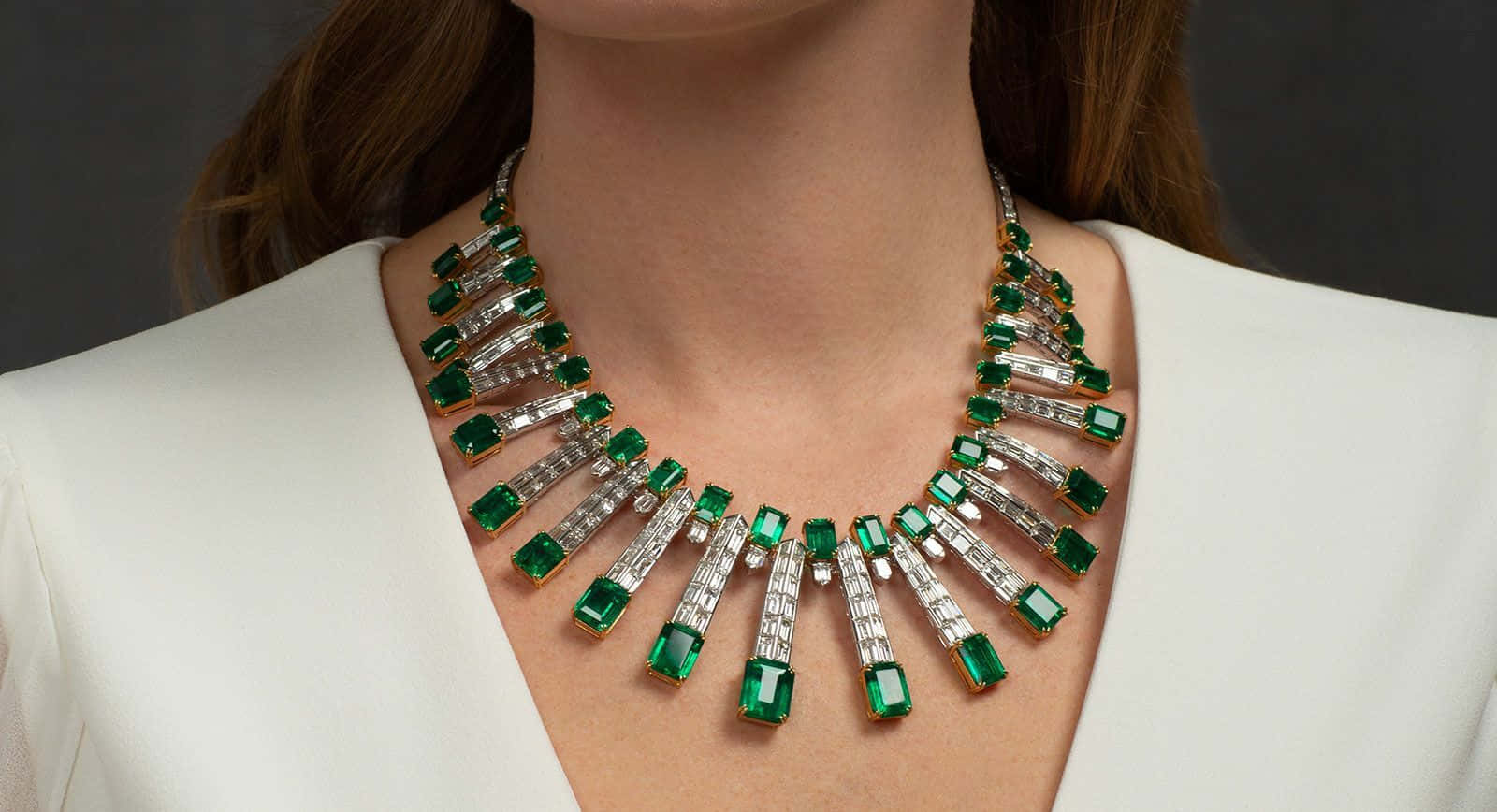 A Woman Wearing A Necklace With Emerald And Diamonds