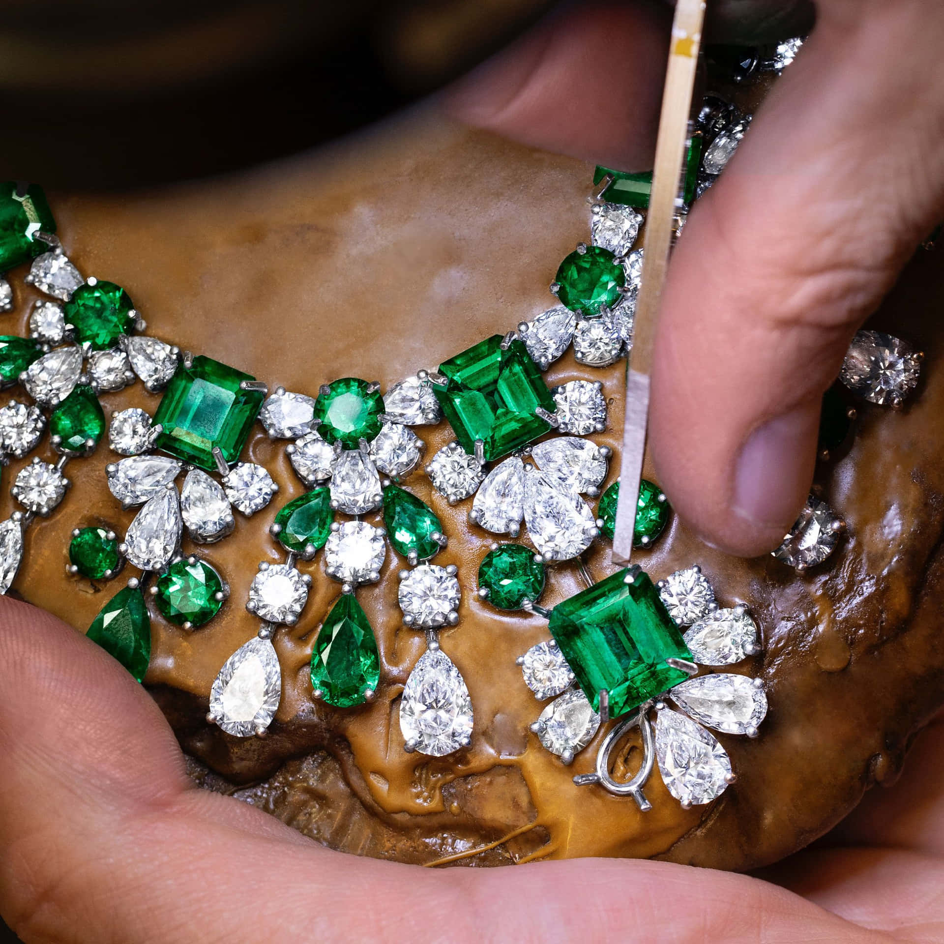 A Person Is Working On An Emerald Necklace