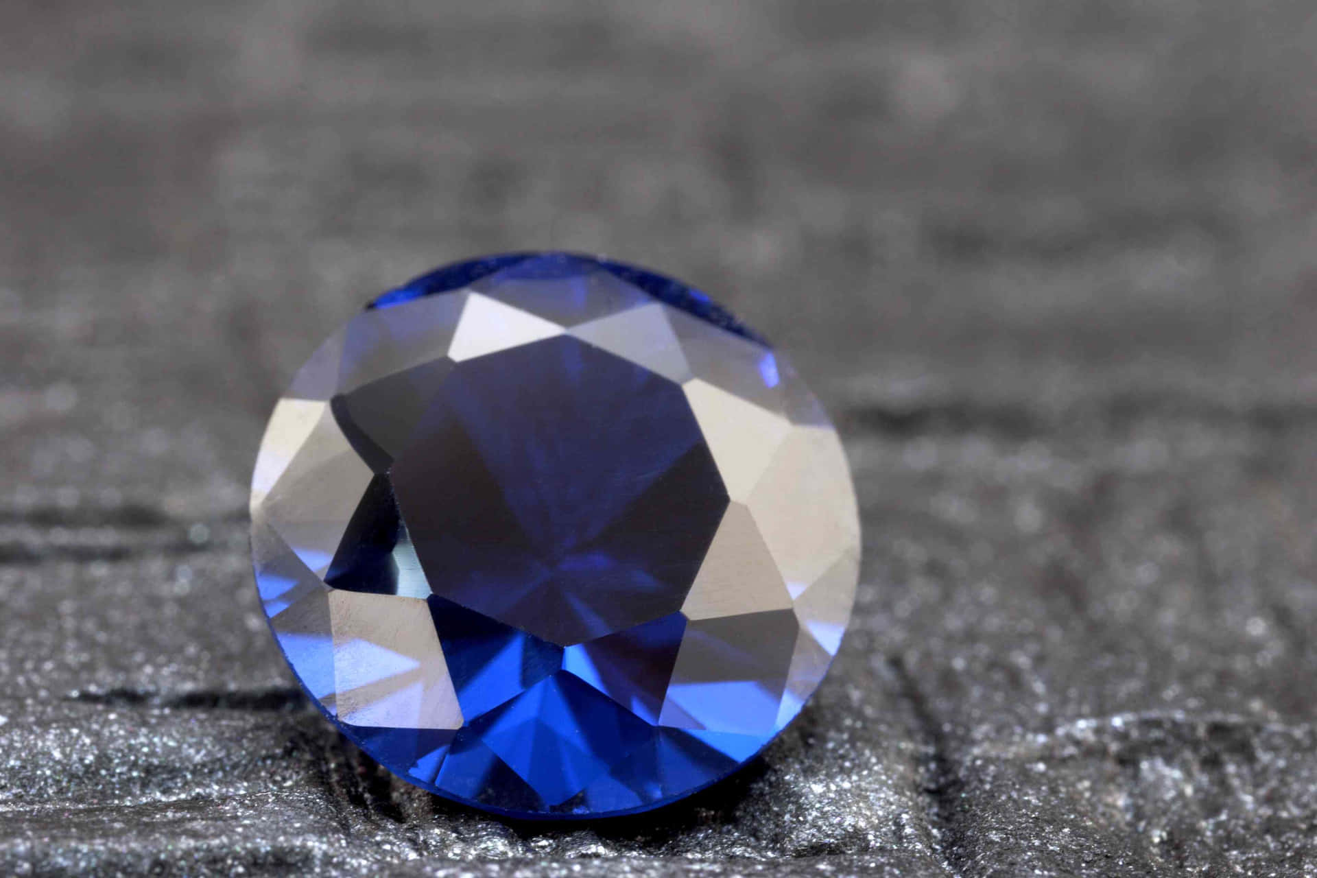 A Blue Sapphire Stone On A Black Surface