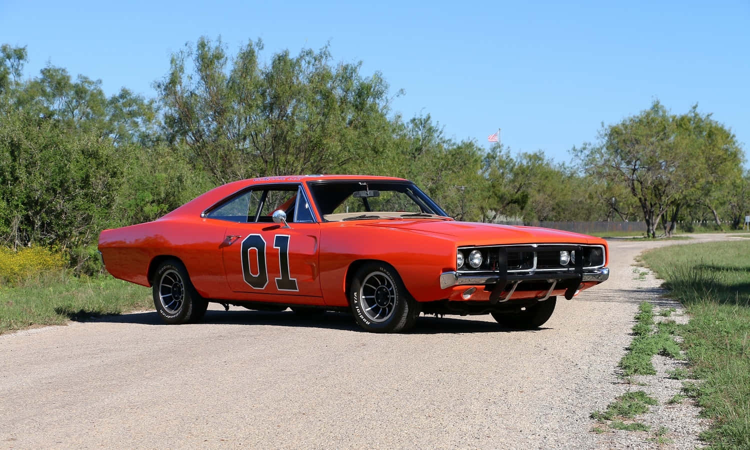 An Orange Muscle Car Is Driving Down A Dirt Road Wallpaper